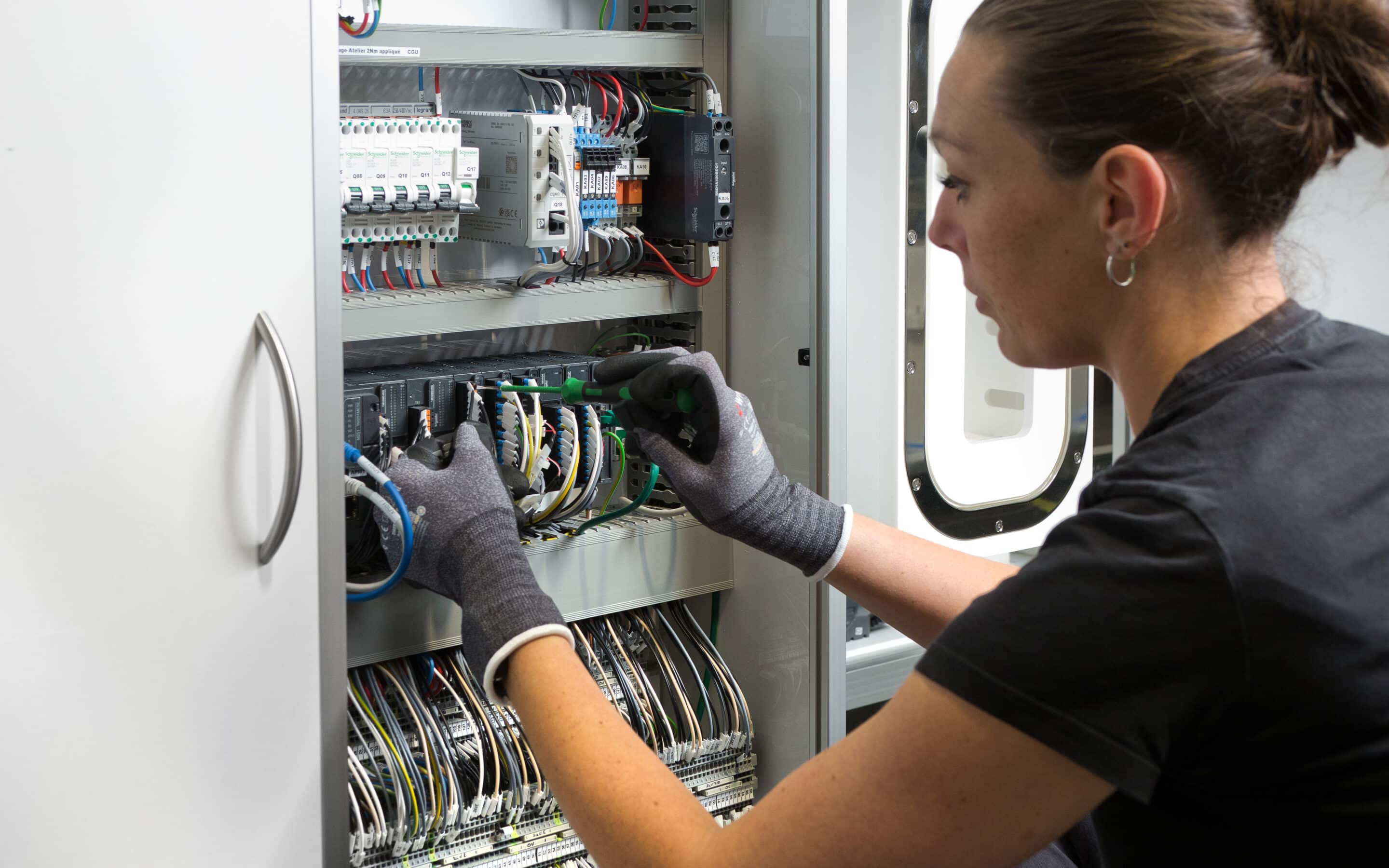 Technicien maintenance JCE Biotechnology intervenant sur une armoire électrique avec câblage et tournevis